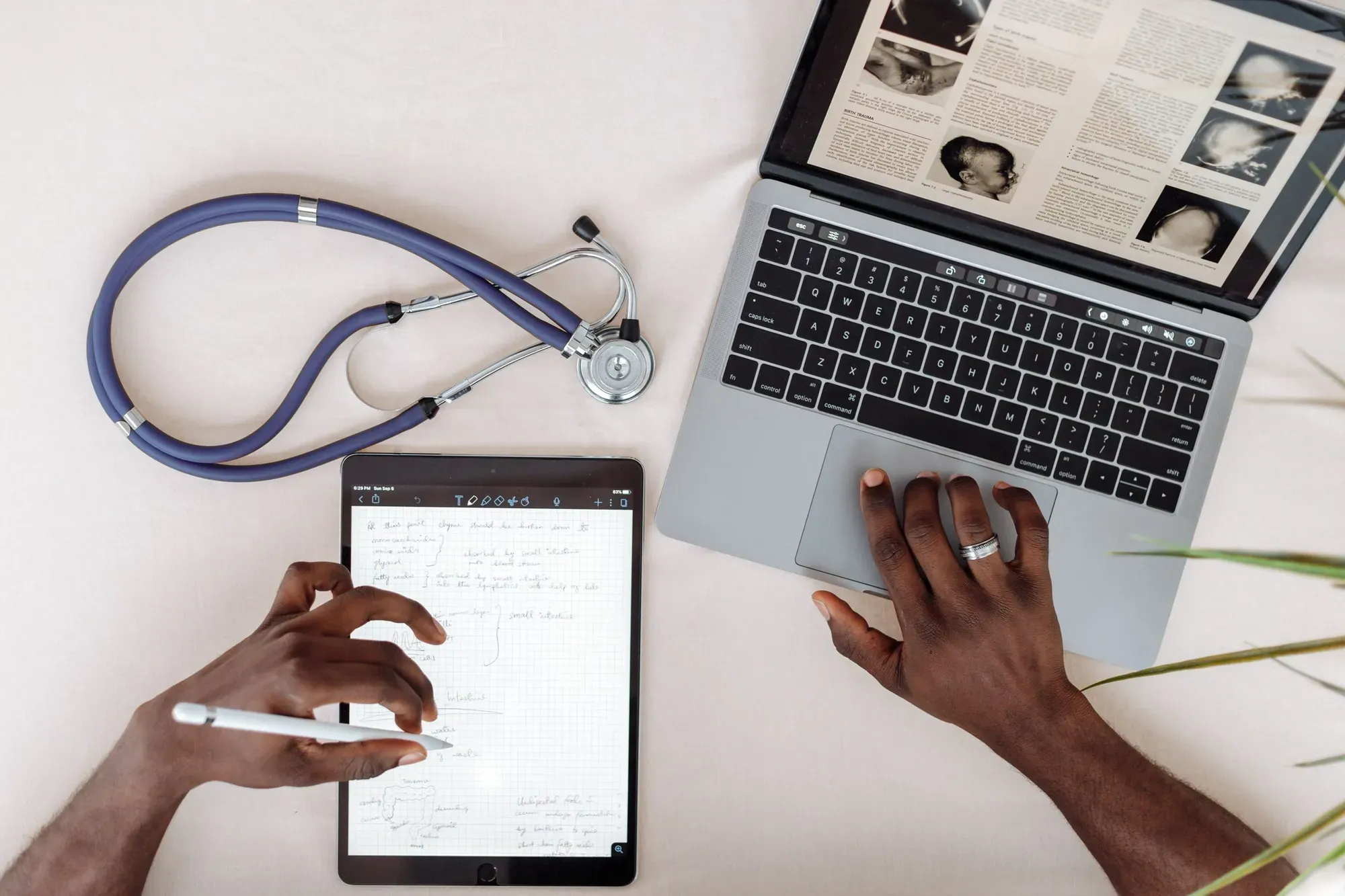 Healthcare professional researching on a tablet and laptop